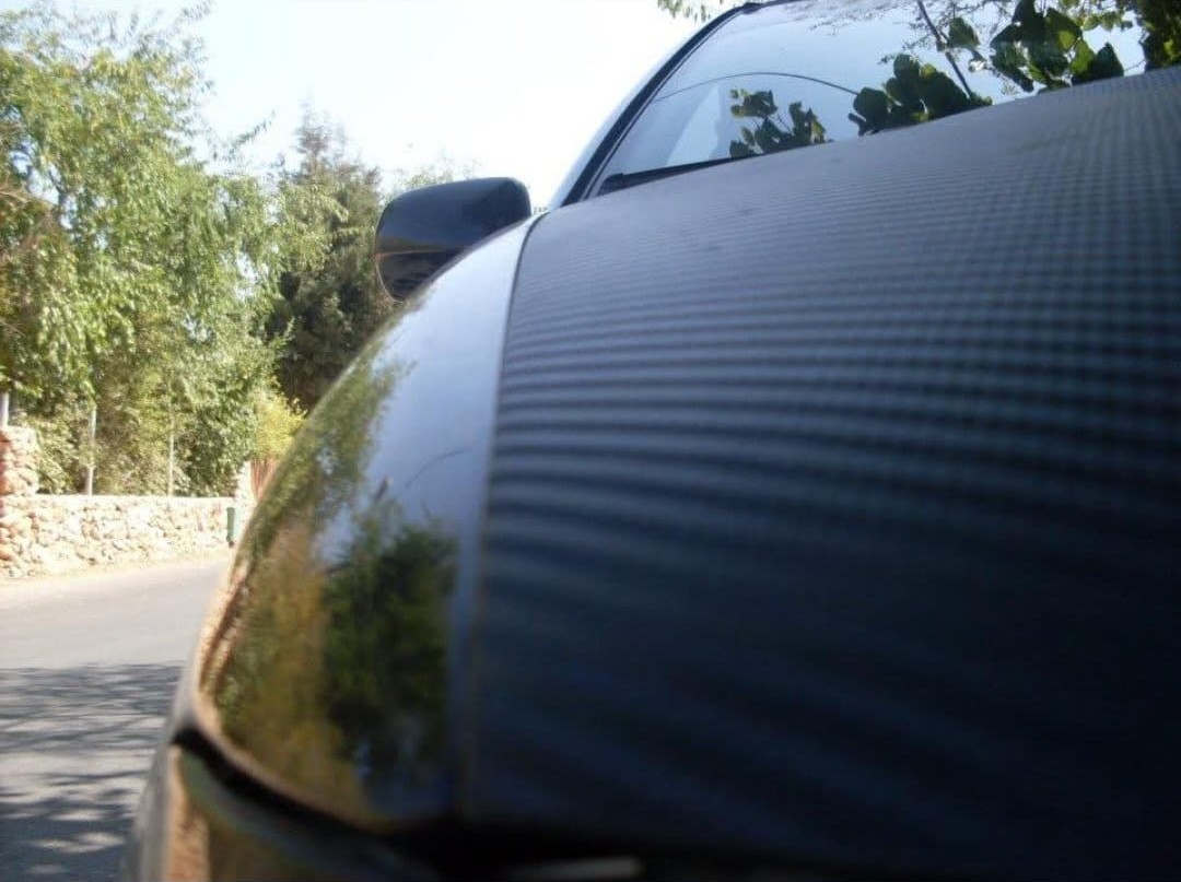 A close view of a dark carbon-fiber-patterned finish on a vehicle.